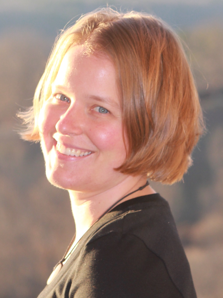 Photo of Elisabeth Krieg smiling wearing a black shirt with mountains in the background.
